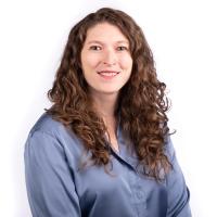 woman with curly brown hair wearing a light blue button-up shirt
